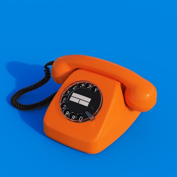 Telefonischer Kontakt Orange Wählscheibentelefon auf blauem Hintergrund.